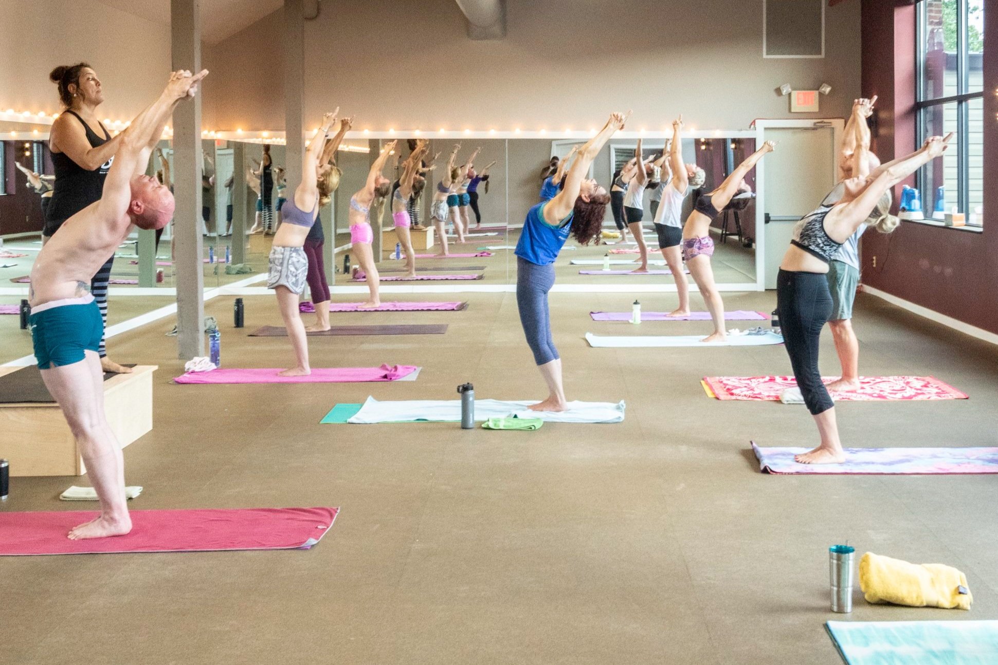 Class working through a mat interval on hot pilates night, lit from the studio windows